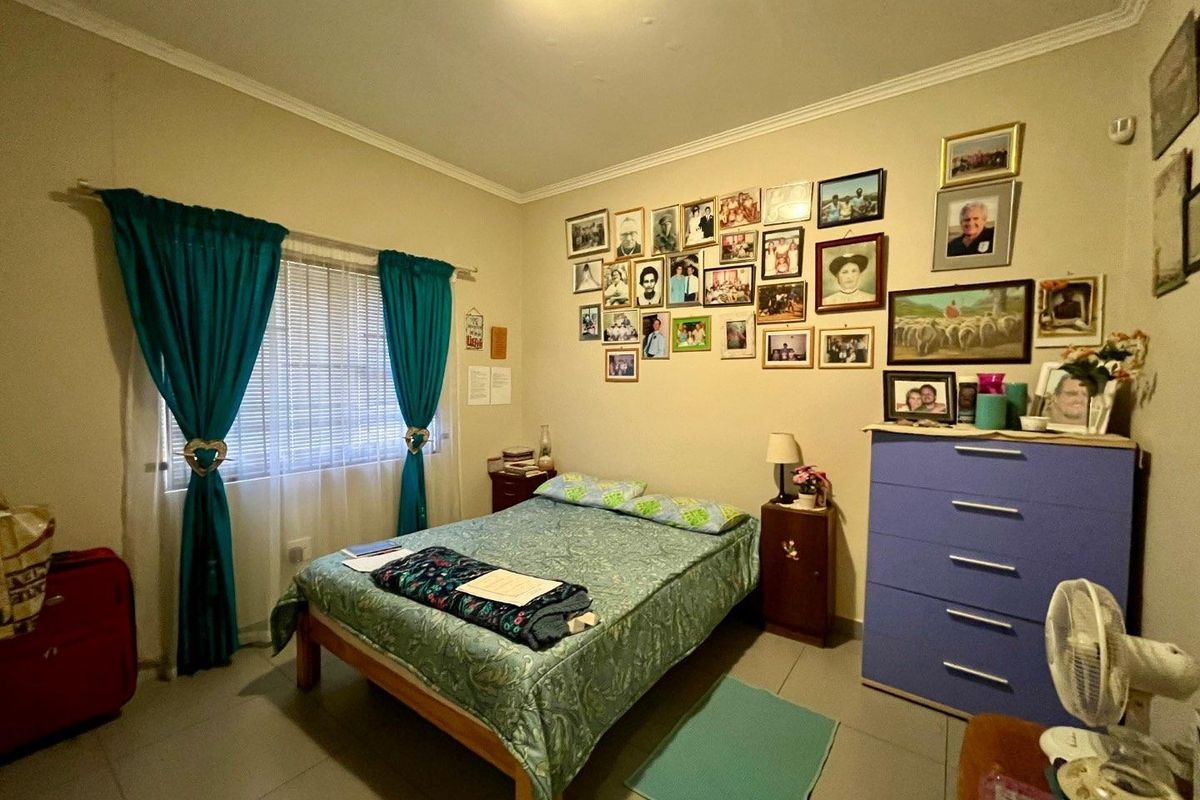 A standard bedroom featuring tiled flooring, a window with fitted curtain rails, and neutral wall finishes.