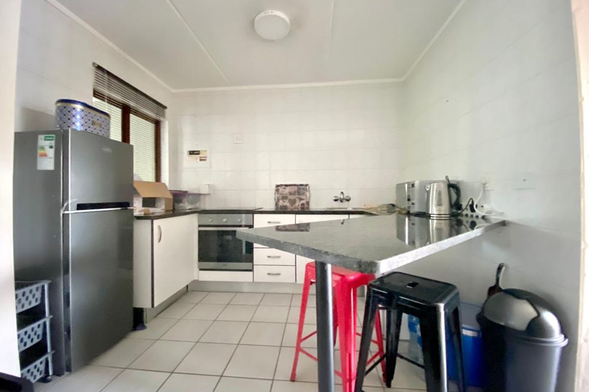 A functional kitchen featuring white cabinetry, a dark countertop, a built-in oven, and tiled flooring.