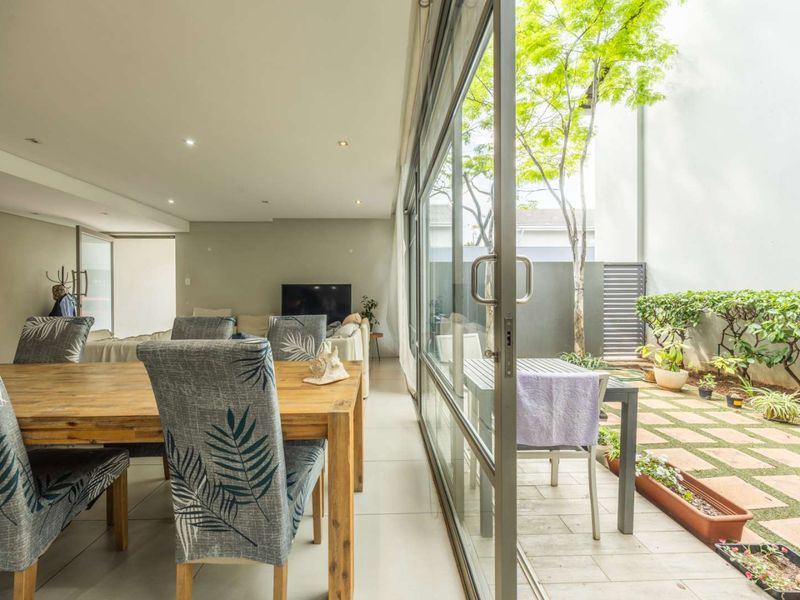 Open plan living and dining area featuring large sliding glass doors that open onto a private paved patio and garden space.