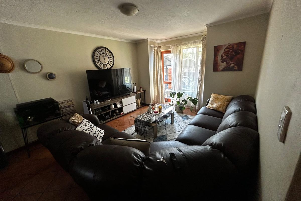 A comfortable living room featuring terracotta floor tiles and a sliding glass door that provides natural light and access to the exterior.