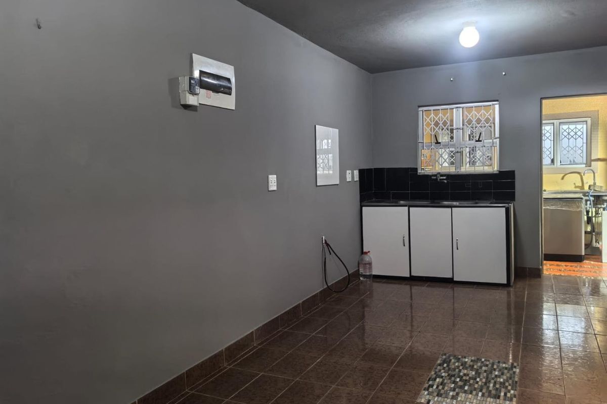 A functional scullery area featuring built-in cabinetry, a sink, and tiled flooring, providing a practical utility space for the home.