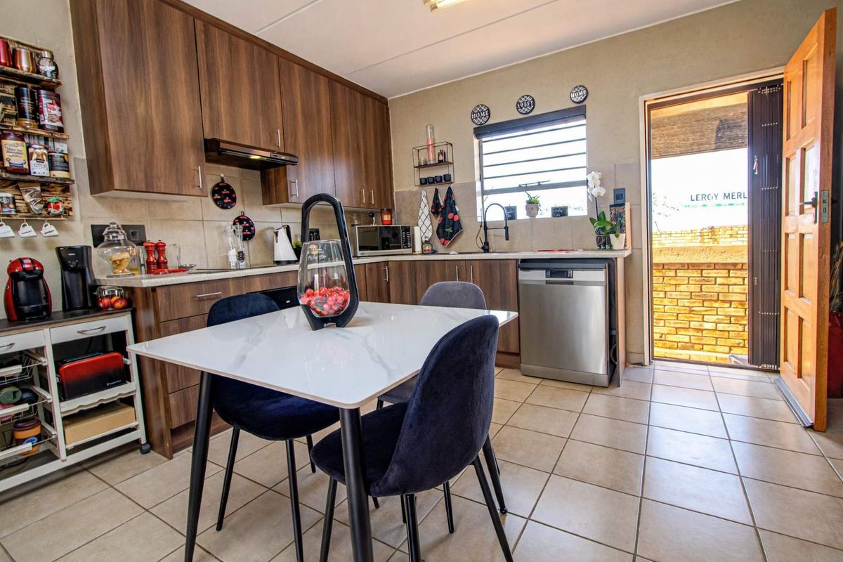 A functional kitchen featuring wood-look cabinetry, tiled flooring, and a built-in extractor fan, with direct access to an outdoor area.