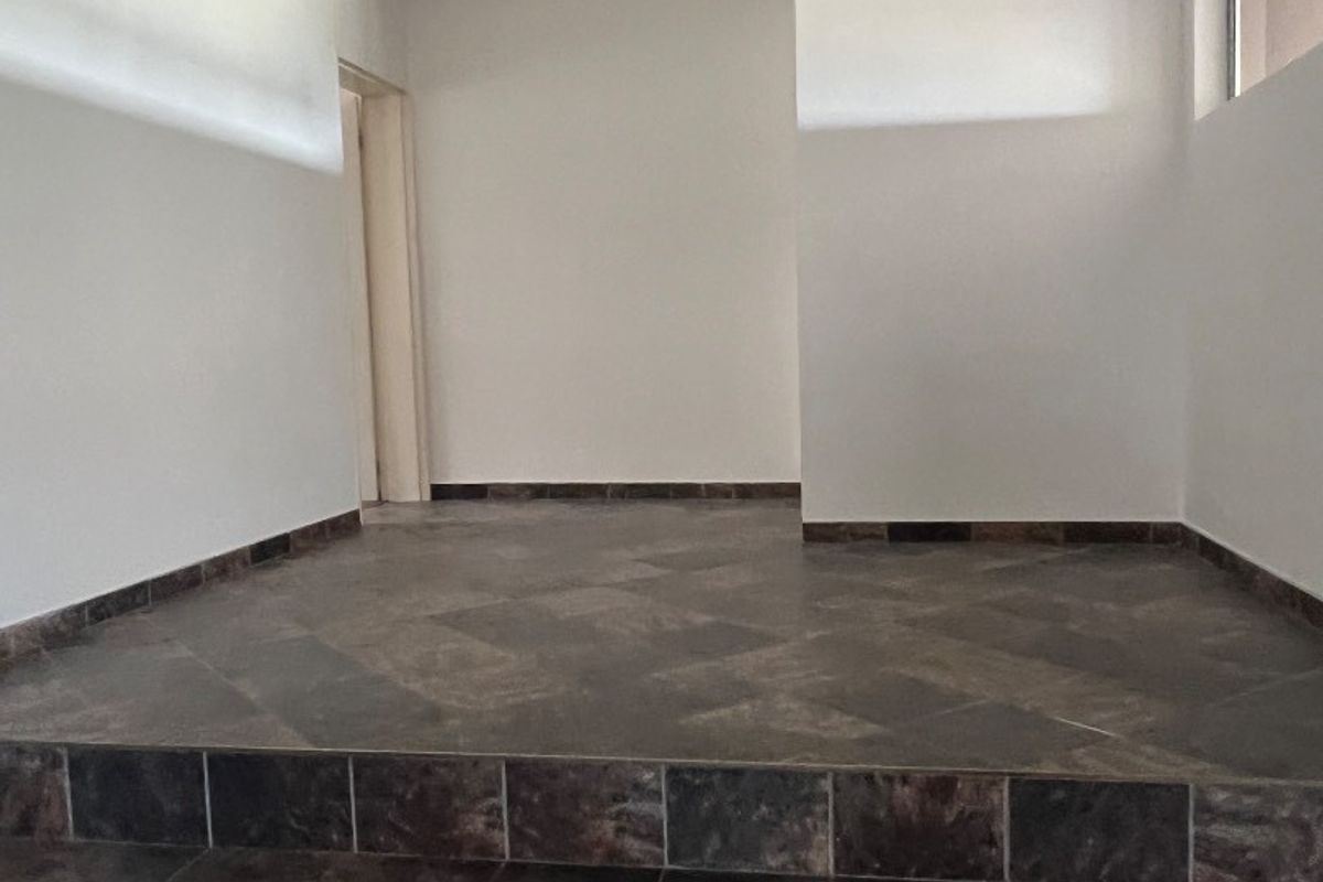 An empty entrance area featuring dark tiled flooring with a stepped transition and neutral wall finishes.