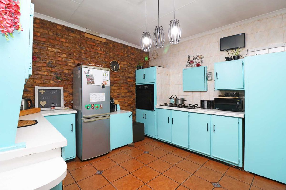 A functional kitchen featuring exposed brick walls, tiled flooring, built-in cabinetry, and integrated cooking appliances including an oven and gas hob.