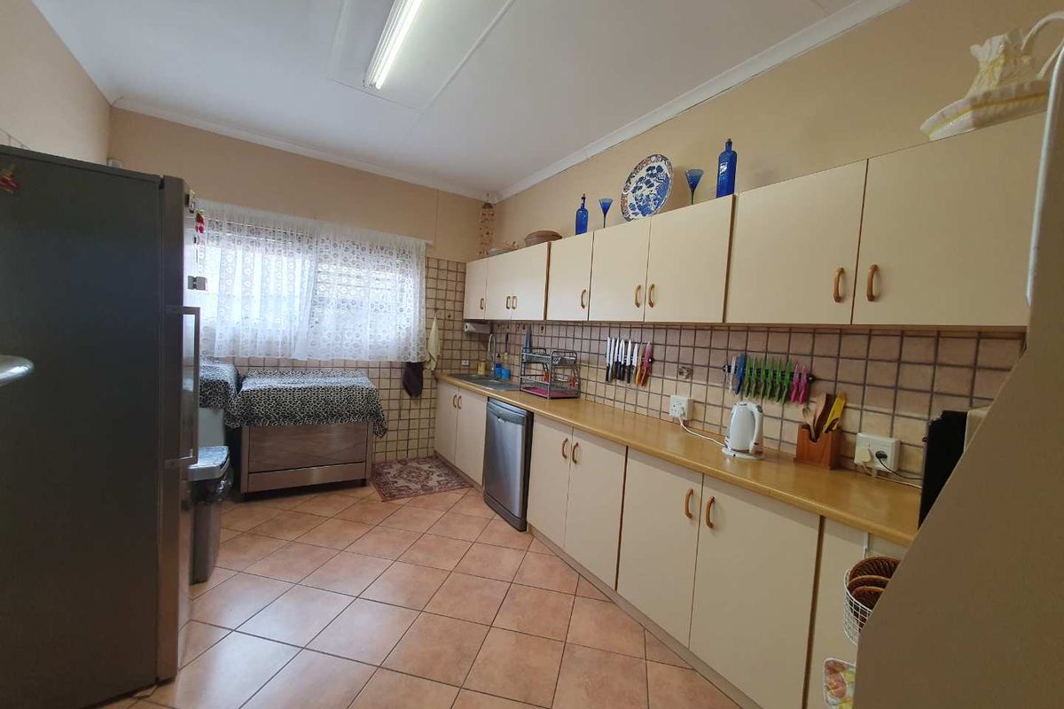 A functional kitchen featuring laminate countertops, tiled flooring, and ample built-in cabinetry with integrated sink and dishwasher space.