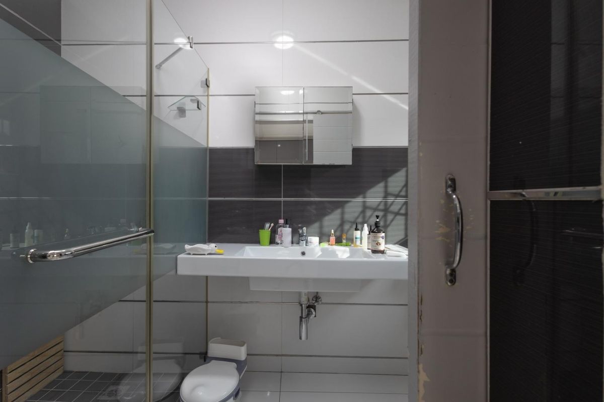 Modern bathroom featuring a wall-mounted vanity sink, mirrored medicine cabinet, and a glass-enclosed shower with contemporary tiled finishes.