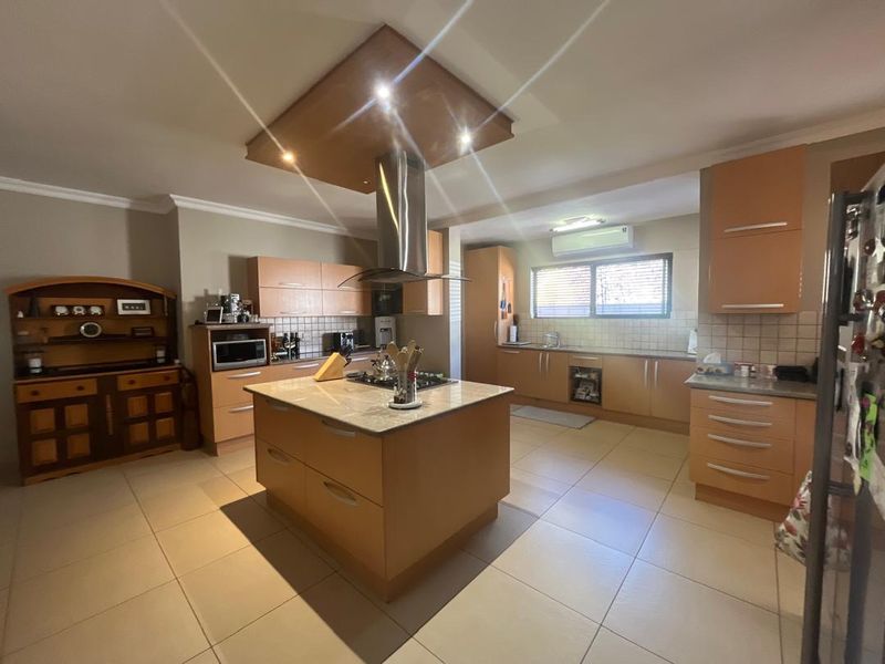 Spacious kitchen featuring a central island, built-in cabinetry, tiled flooring, and a stainless steel extractor fan.