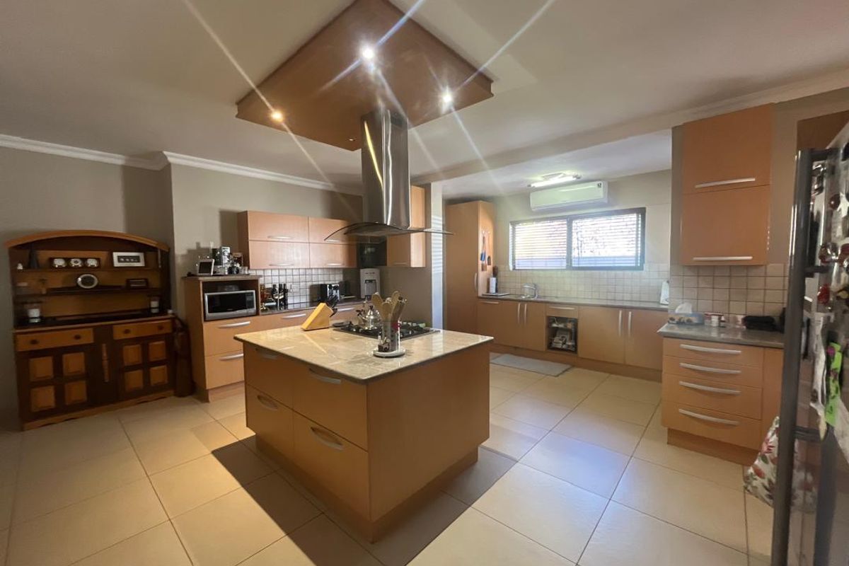 Spacious kitchen featuring a central island, built-in cabinetry, tiled flooring, and a stainless steel extractor fan.