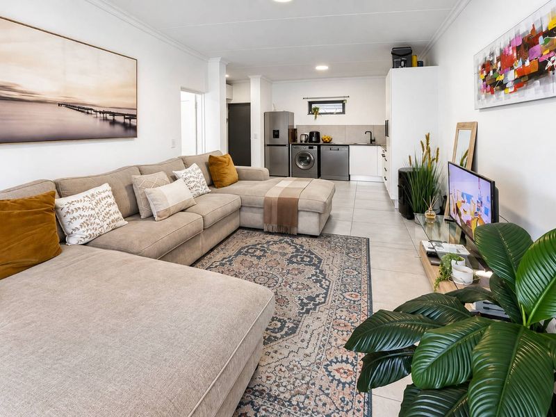 An open-plan living area featuring tiled flooring, recessed lighting, and a functional kitchen space with integrated cabinetry and sink.
