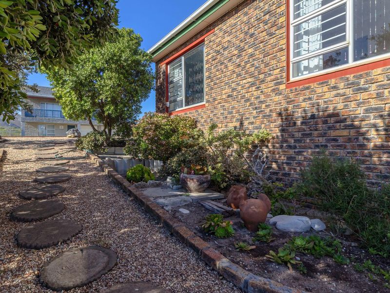 A side view of the property featuring a face brick exterior, security bars on windows, and a landscaped garden with a gravel pathway.