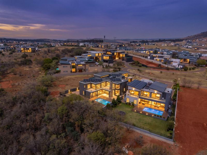 Aerial view of a modern residential estate featuring luxury homes with swimming pools, solar panels, and landscaped outdoor areas at twilight.