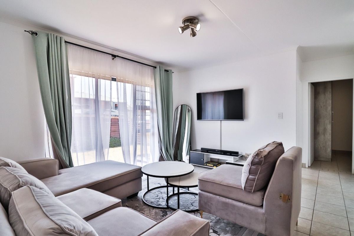 A bright and comfortable living room featuring large sliding glass doors that provide natural light and direct access to the outdoor area.