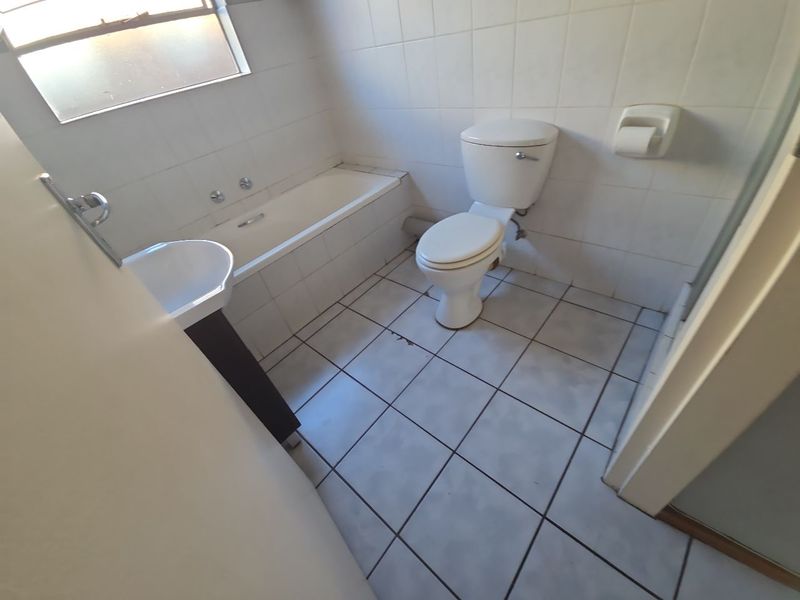 A functional bathroom featuring a bathtub, pedestal basin, and toilet with tiled finishes throughout.
