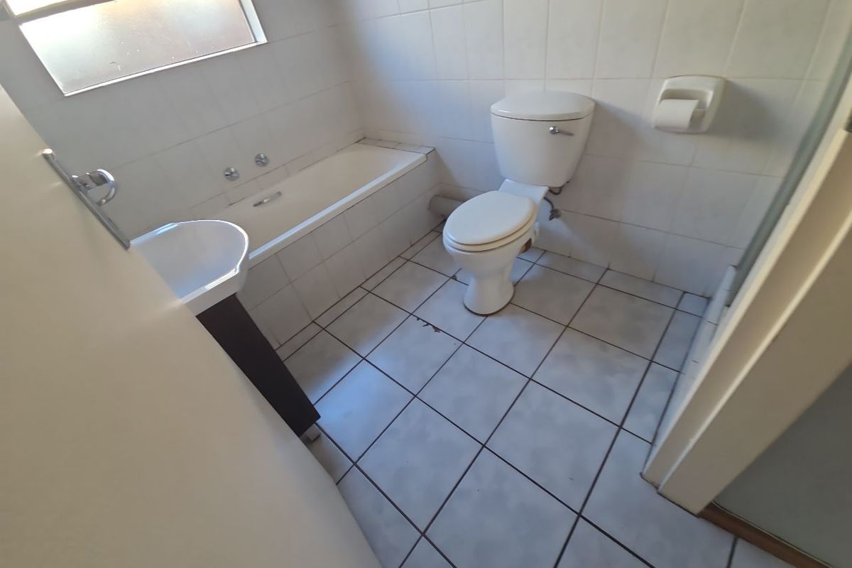 A functional bathroom featuring a bathtub, pedestal basin, and toilet with tiled finishes throughout.