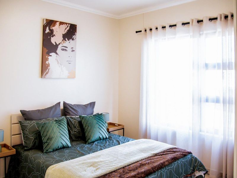 A well-lit bedroom featuring neutral walls, coving, and a large window with installed curtain rod.