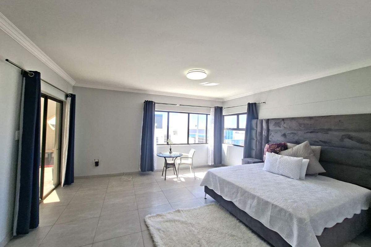 Spacious bedroom featuring large windows, tiled flooring, and direct access to an outdoor patio area.