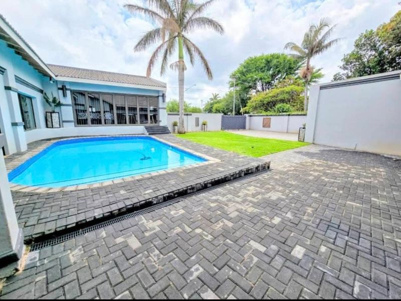 A well-maintained outdoor area featuring a swimming pool, paved patio space, and a private garden enclosed by boundary walls.