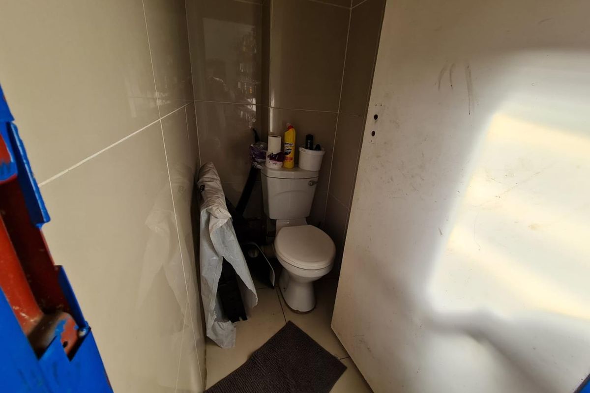 A small, compact restroom featuring tiled walls and a standard toilet fixture, currently showing signs of wear and maintenance requirements.