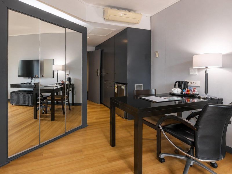 A well-maintained bedroom featuring laminate flooring, mirrored built-in cupboards, and a wall-mounted air conditioning unit for climate control.