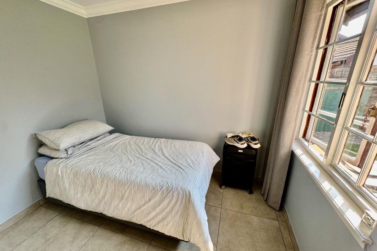 A bedroom featuring tiled flooring, neutral wall paint, and a window with natural light.
