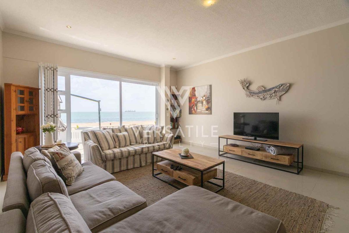 Spacious living room featuring large sliding glass doors that open to a scenic beach view, providing ample natural light and seamless indoor-outdoor flow.