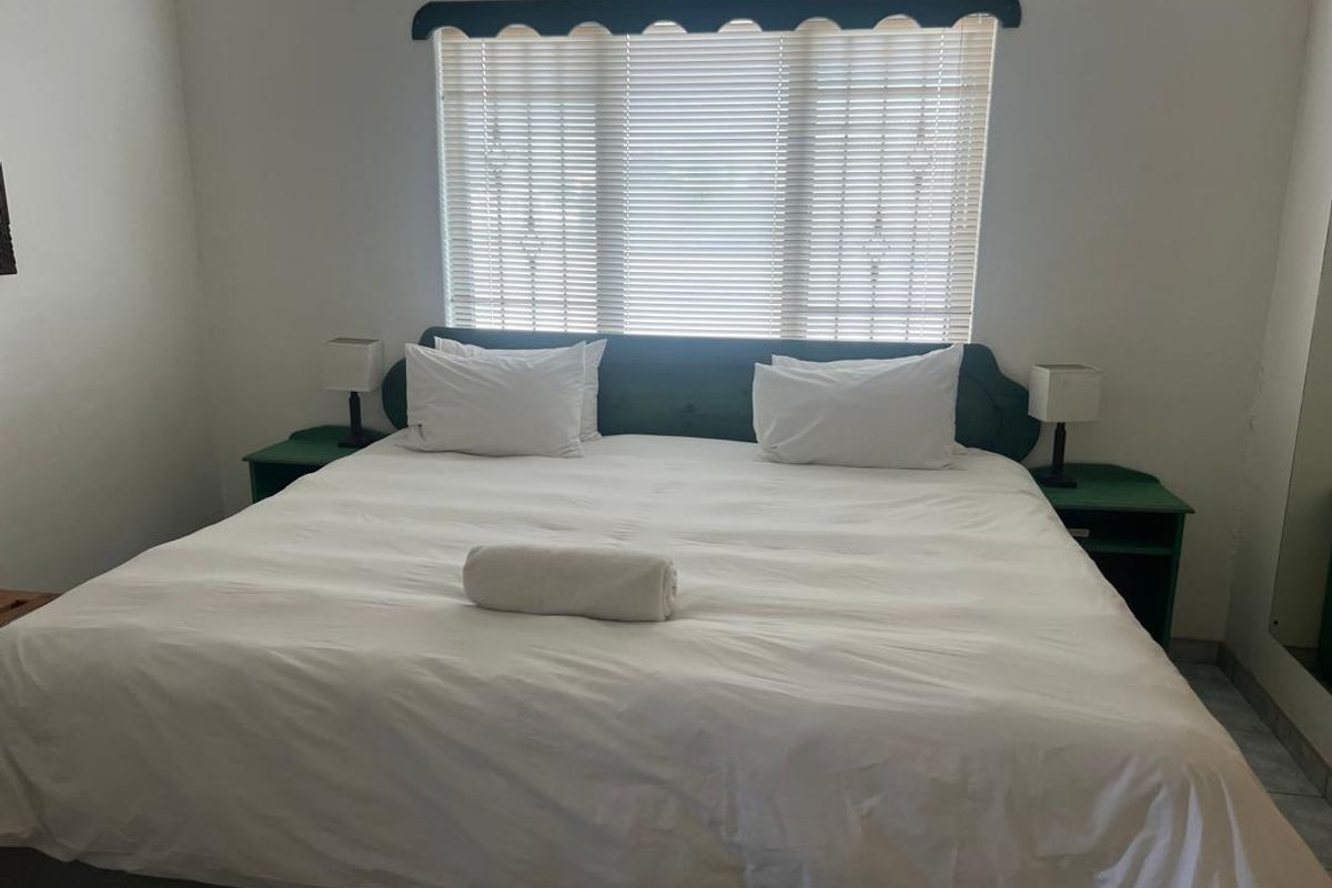 A bedroom featuring a built-in headboard with integrated bedside tables and venetian blinds.