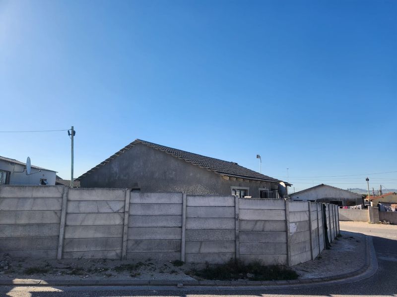 Rear view of the property featuring a tiled roof and a precast concrete boundary wall enclosing the yard area.