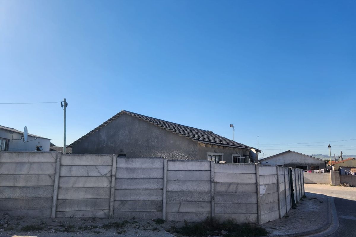 Rear view of the property featuring a tiled roof and a precast concrete boundary wall enclosing the yard area.