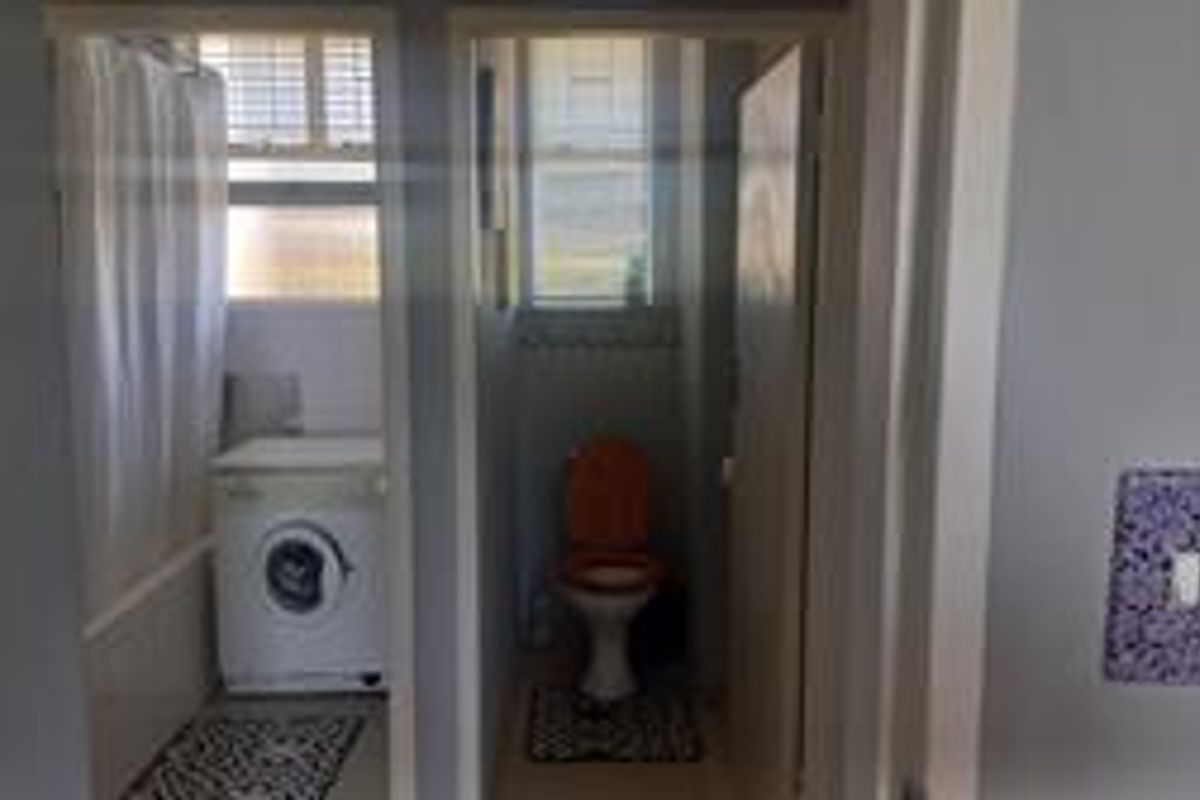 A functional bathroom and separate toilet area featuring basic sanitary ware and plumbing connections for laundry appliances.