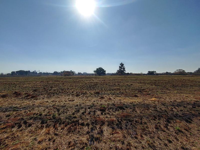 A wide-angle view of a vacant commercial land plot featuring flat, open terrain under a clear sky.