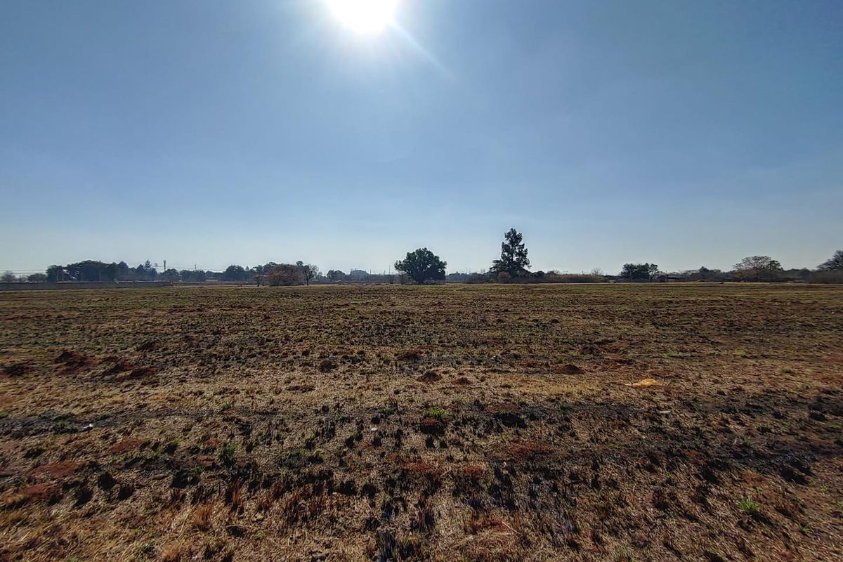 A wide-angle view of a vacant commercial land plot featuring flat, open terrain under a clear sky.