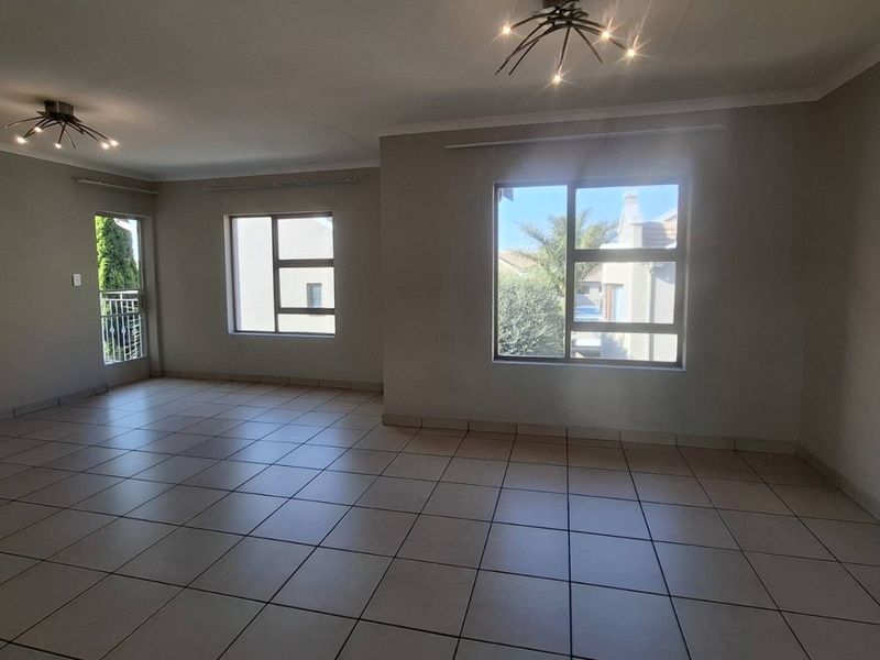 Spacious, light-filled living area featuring neutral tiled flooring, large aluminium windows, and modern ceiling lighting, offering a clean and versatile blank canvas.
