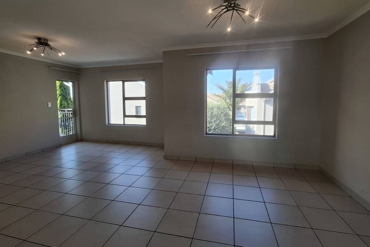 Spacious, light-filled living area featuring neutral tiled flooring, large aluminium windows, and modern ceiling lighting, offering a clean and versatile blank canvas.