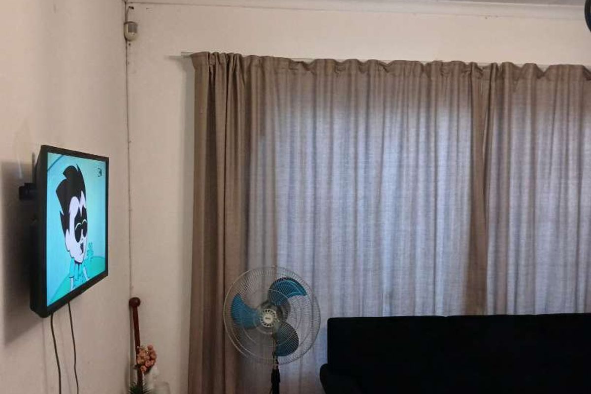 A living room featuring tiled flooring, neutral wall finishes, and a wall-mounted television setup.
