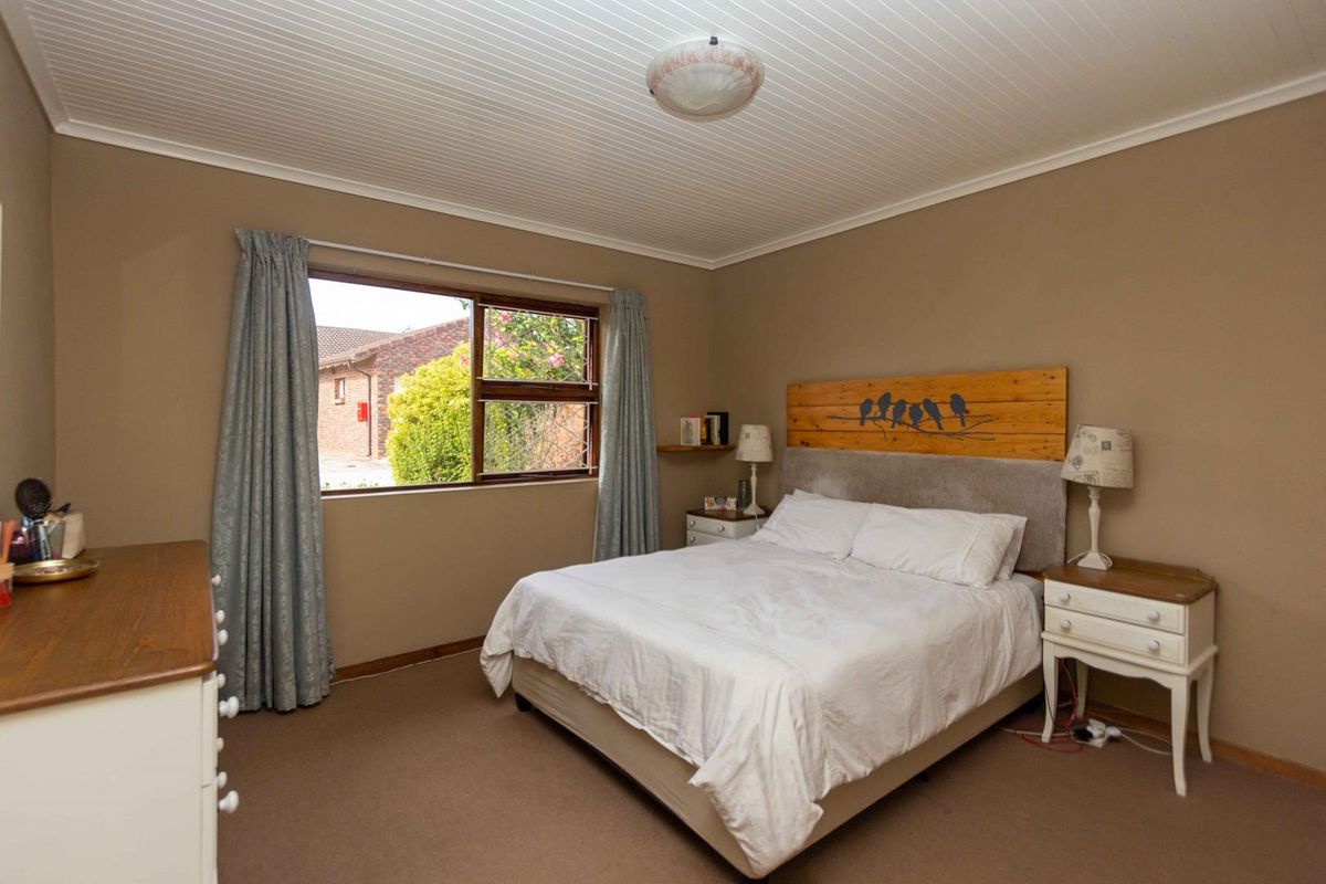 A well-maintained bedroom featuring neutral wall tones, carpeted flooring, and a classic beadboard ceiling with a central light fixture.