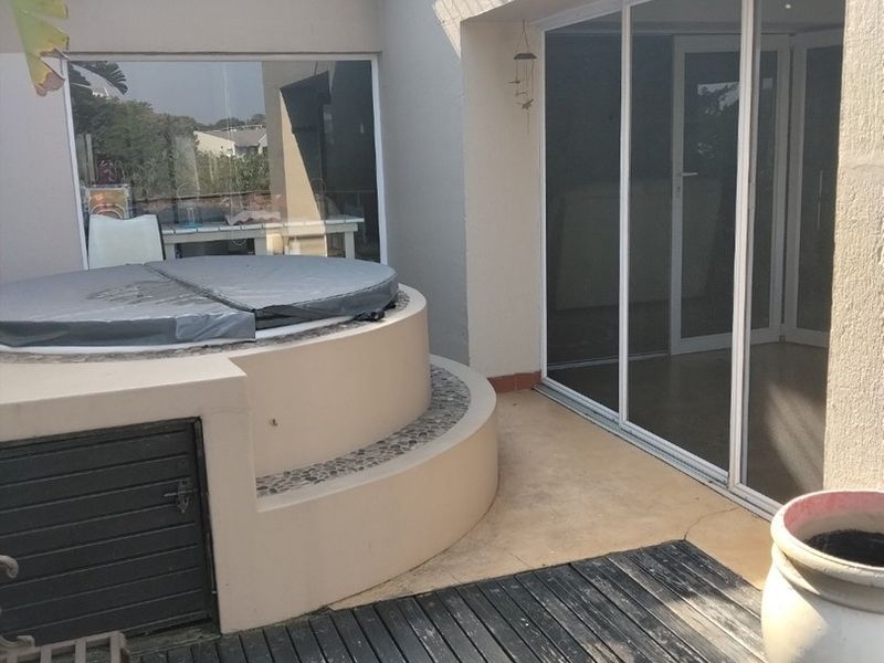 Outdoor patio area featuring a built-in jacuzzi, timber decking, and sliding glass door access to the interior living space.