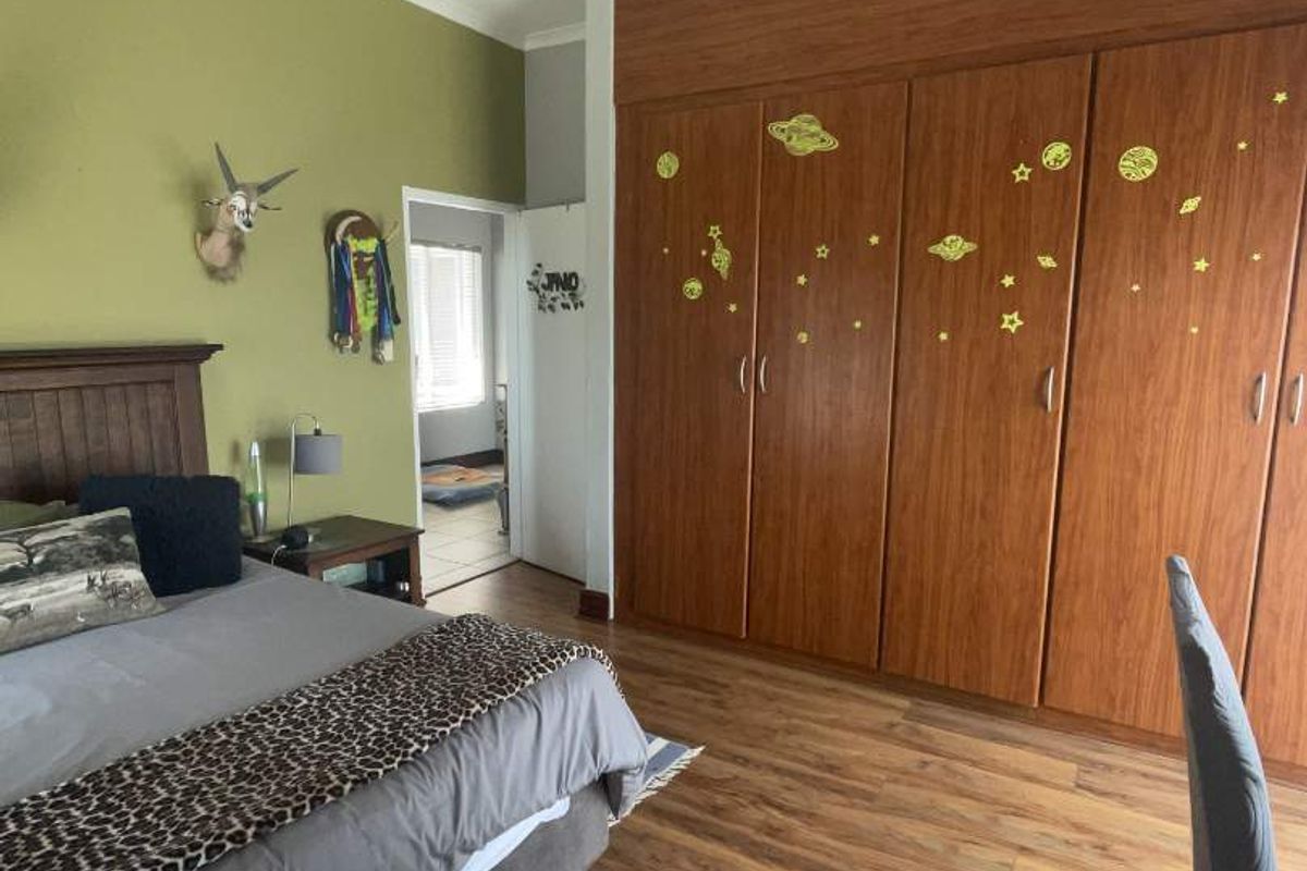 A bedroom featuring wood-look laminate flooring and extensive built-in wooden cabinetry providing ample storage space.