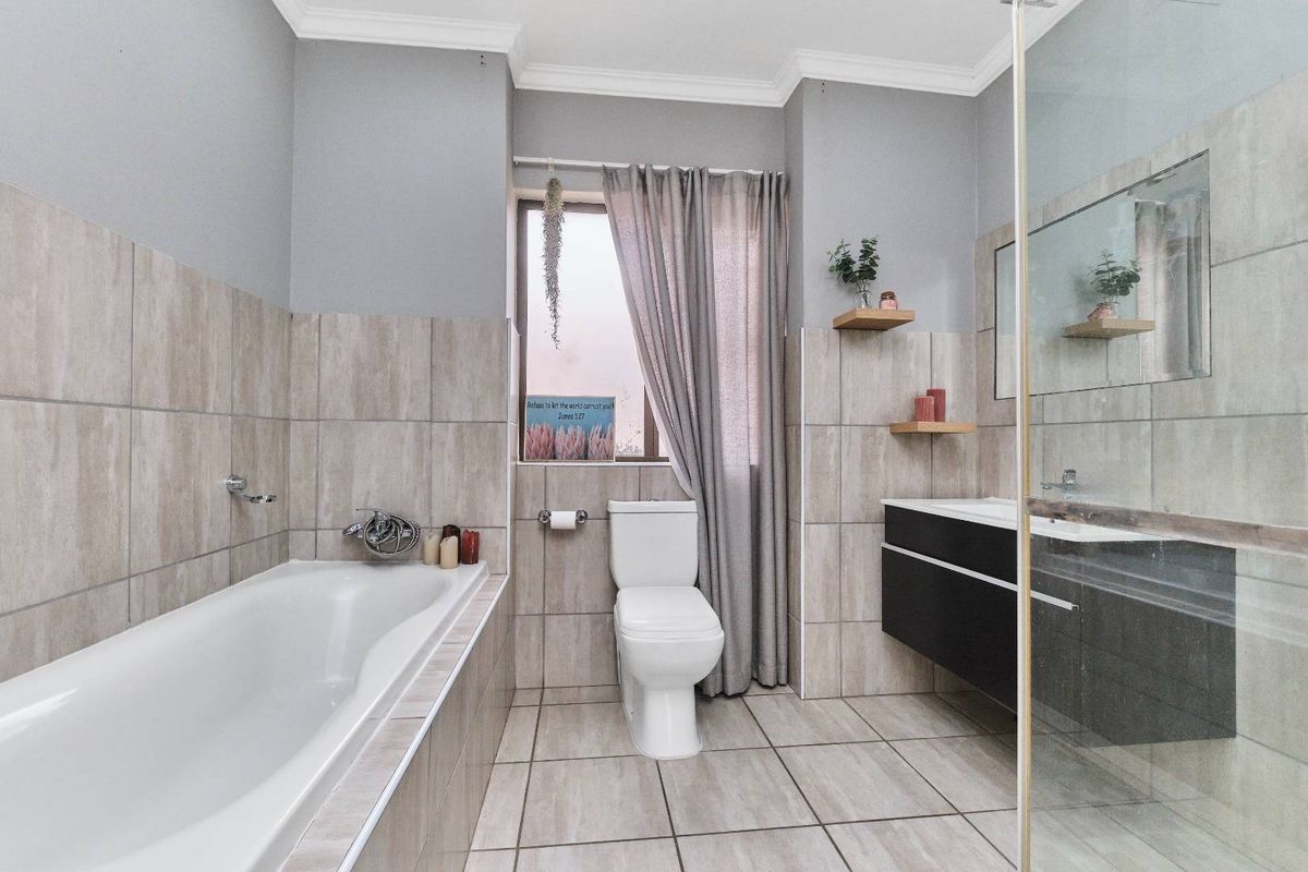 Modern bathroom featuring a built-in bathtub, wall-mounted vanity, glass-enclosed shower, and neutral floor-to-ceiling tiling.