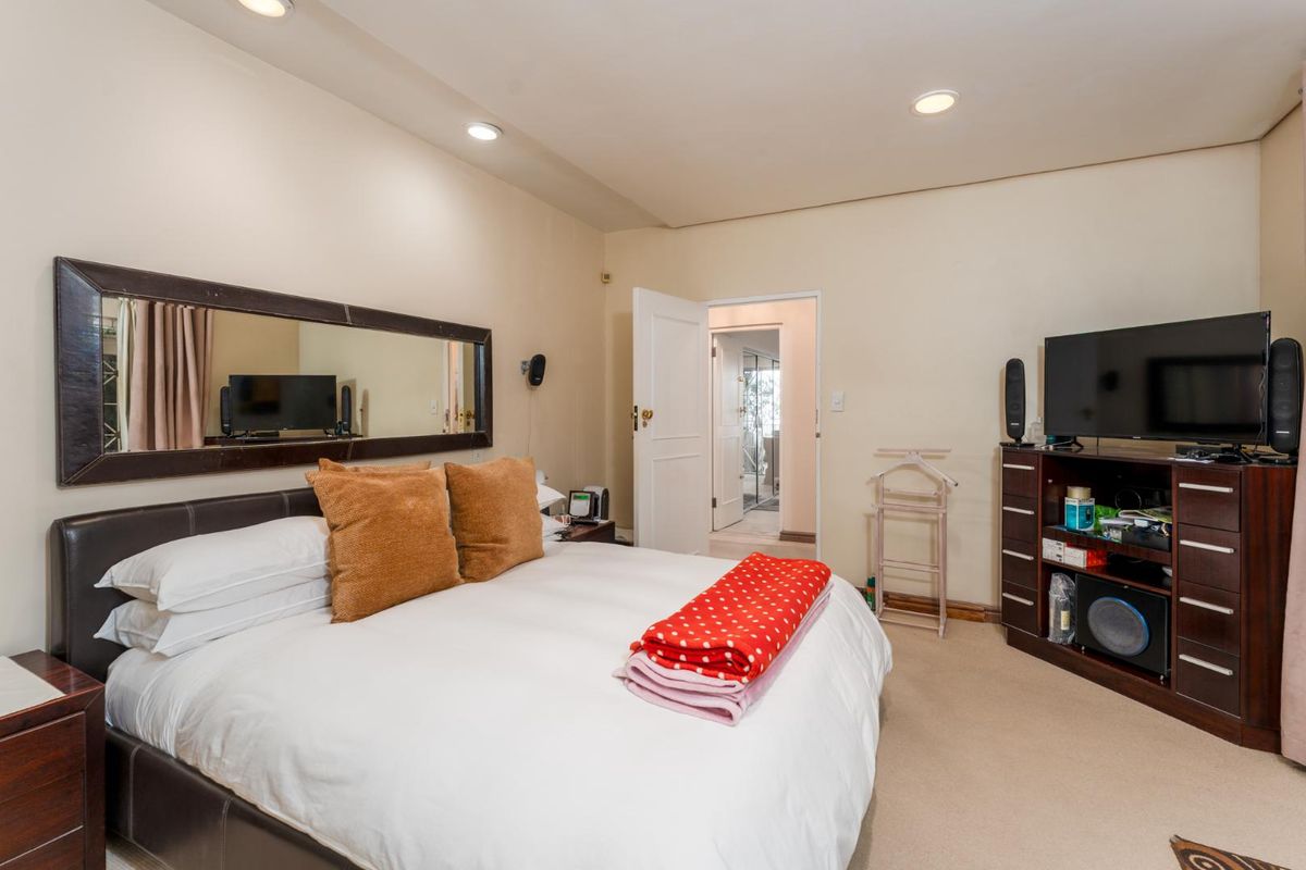 A well-proportioned bedroom featuring recessed ceiling lighting, neutral carpeting, and an en-suite doorway, providing a comfortable and functional living space.