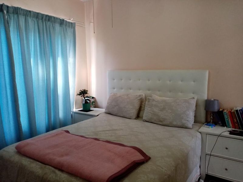 A standard bedroom featuring a neutral wall finish and window with curtain rail, providing a functional sleeping space.