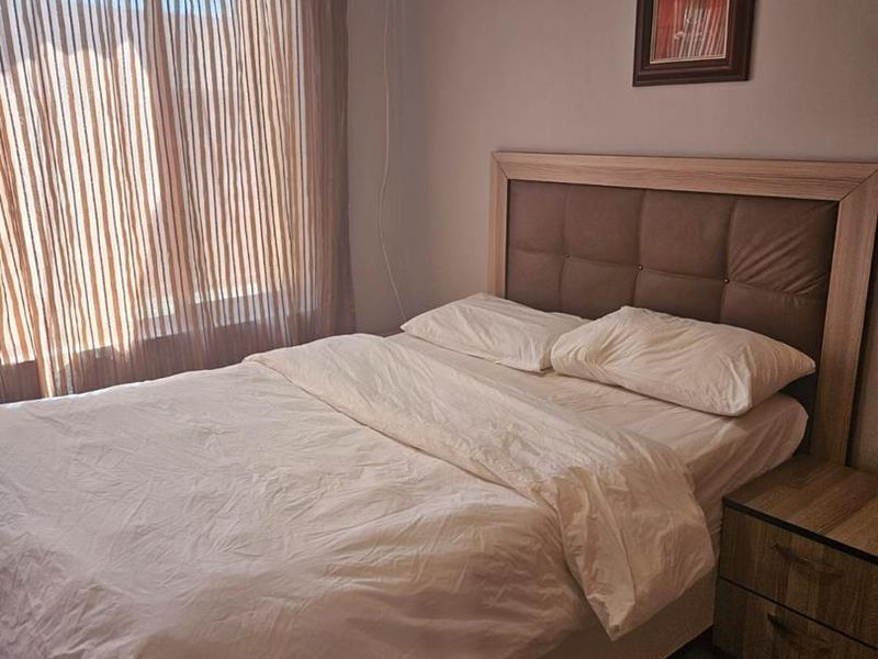 A bedroom featuring tiled flooring, crown molding, and a sliding glass door with curtains, providing natural light and access to the exterior.