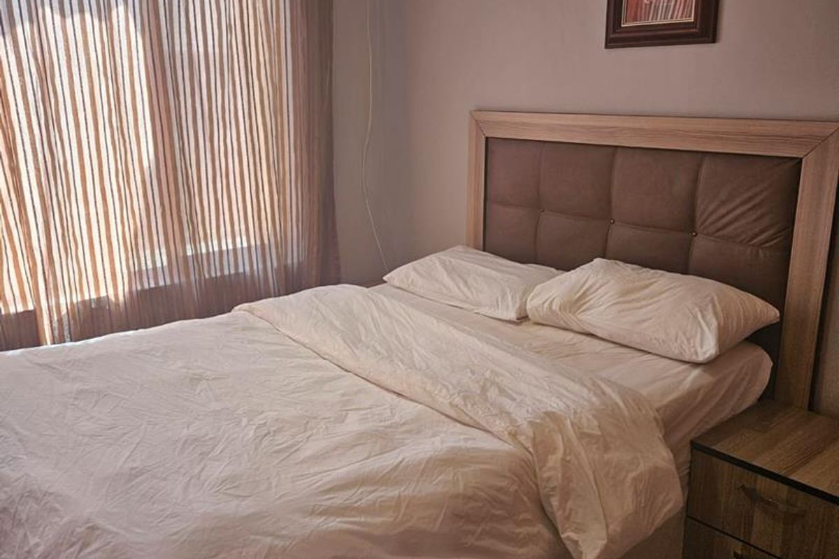 A bedroom featuring tiled flooring, crown molding, and a sliding glass door with curtains, providing natural light and access to the exterior.
