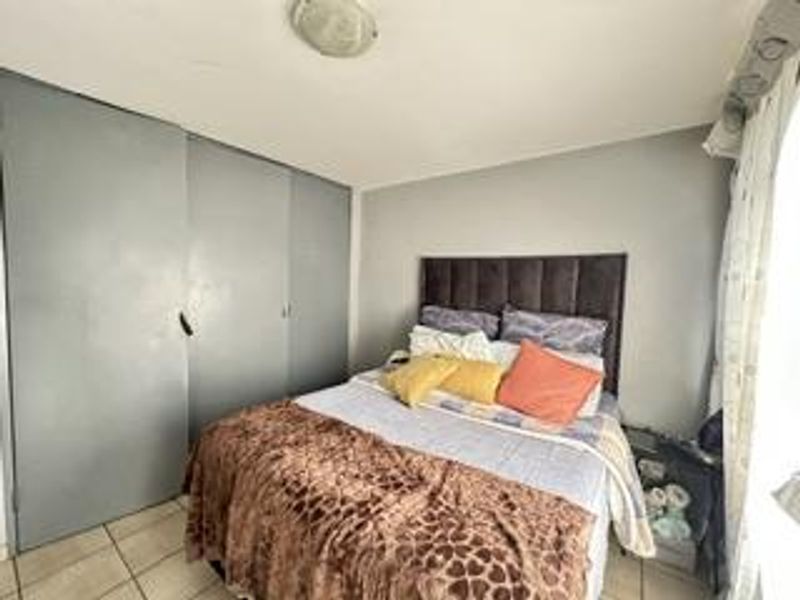 A bedroom featuring tiled flooring and built-in cupboards, providing functional storage space within the apartment.