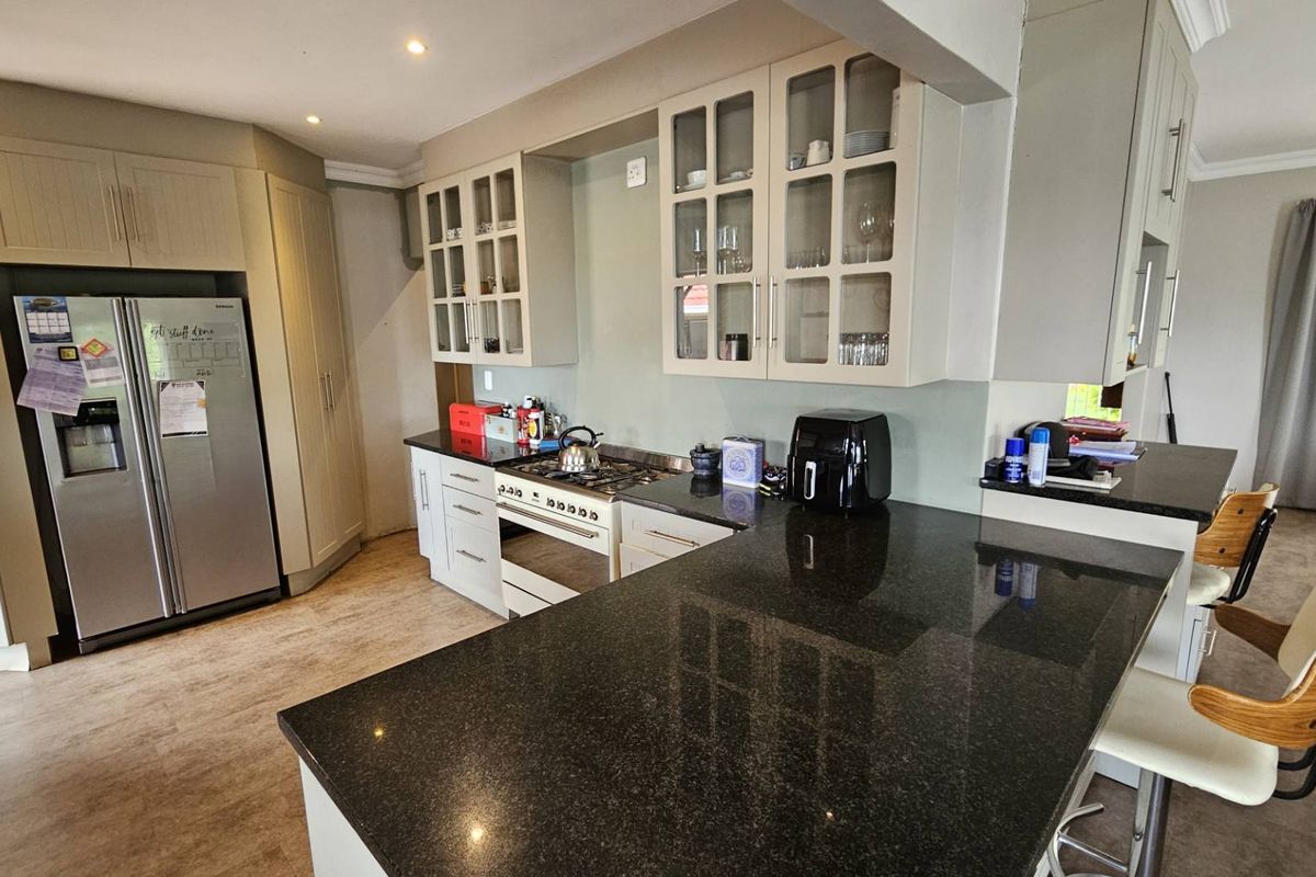 A well-appointed kitchen featuring granite countertops, built-in cabinetry, and a gas hob, seamlessly integrated into an open-plan living space.
