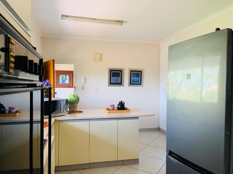 A functional kitchen featuring built-in cabinetry, an integrated oven, tiled flooring, and a breakfast counter, offering a clean and practical layout.