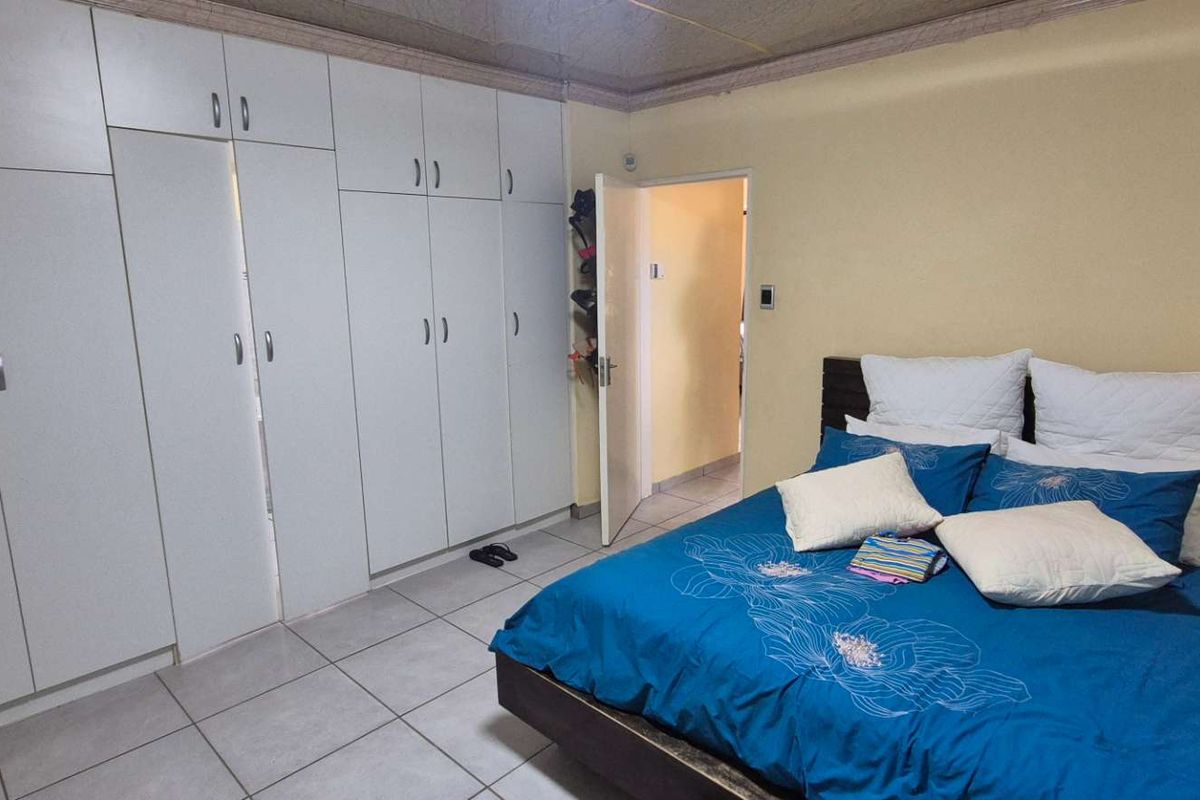 A bedroom featuring built-in floor-to-ceiling white cabinetry, tiled flooring, and a doorway leading to an adjacent room.