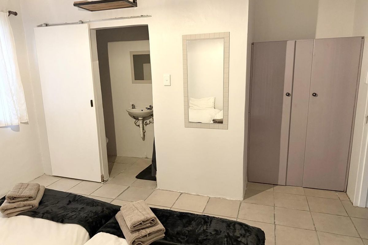 Bedroom featuring tiled flooring, built-in wardrobe, and an en-suite bathroom with a wall-mounted basin.