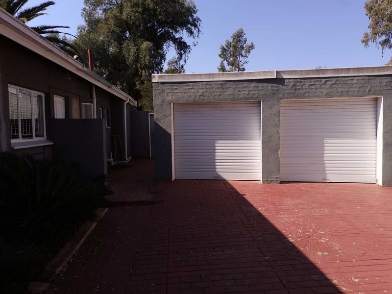 A double garage with white roller doors and a paved driveway area, showing standard exterior maintenance.