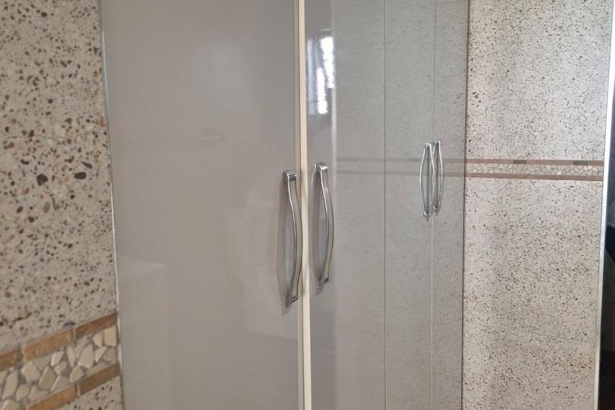 A view of built-in cabinetry with high-gloss finish, complemented by textured stone-look wall tiling and wood-look flooring.