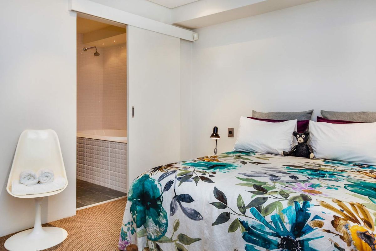 A well-maintained bedroom featuring a sliding door entry to an en-suite bathroom with a tiled bathtub and shower fixture.
